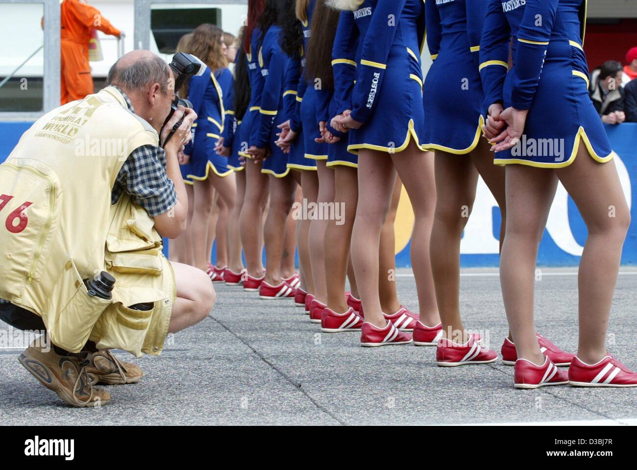 (Afp) - Un photographe prend une photo d'une ligne de Grid Girls à la piste de course de Formule 1 à Imola, Italie, le 20 avril 2003. Banque D'Images