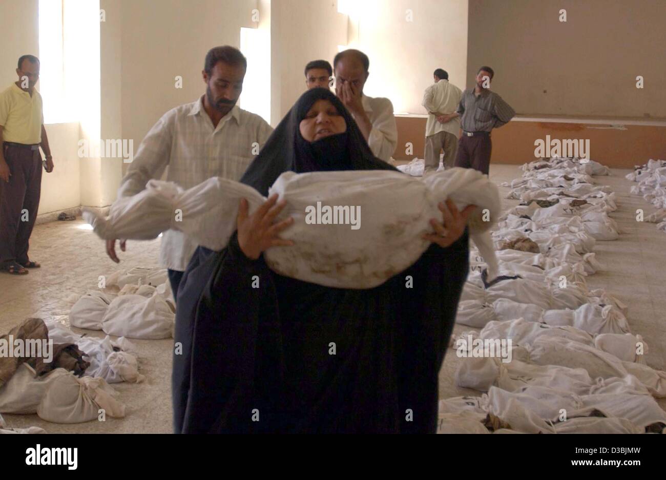 (Afp) - Une femme irakienne porte un sac contenant un corps découvert dans une fosse commune à 50 km au sud de Bagdad et affiché pour l'identification dans la ville voisine de Al-Mesayeb, Iraq, 24 mai 20003. Dans le centre de l'Irak, les Irakiens tentent d'identifier leurs proches dont les corps ont été creusés à partir de plusieurs g masse Banque D'Images