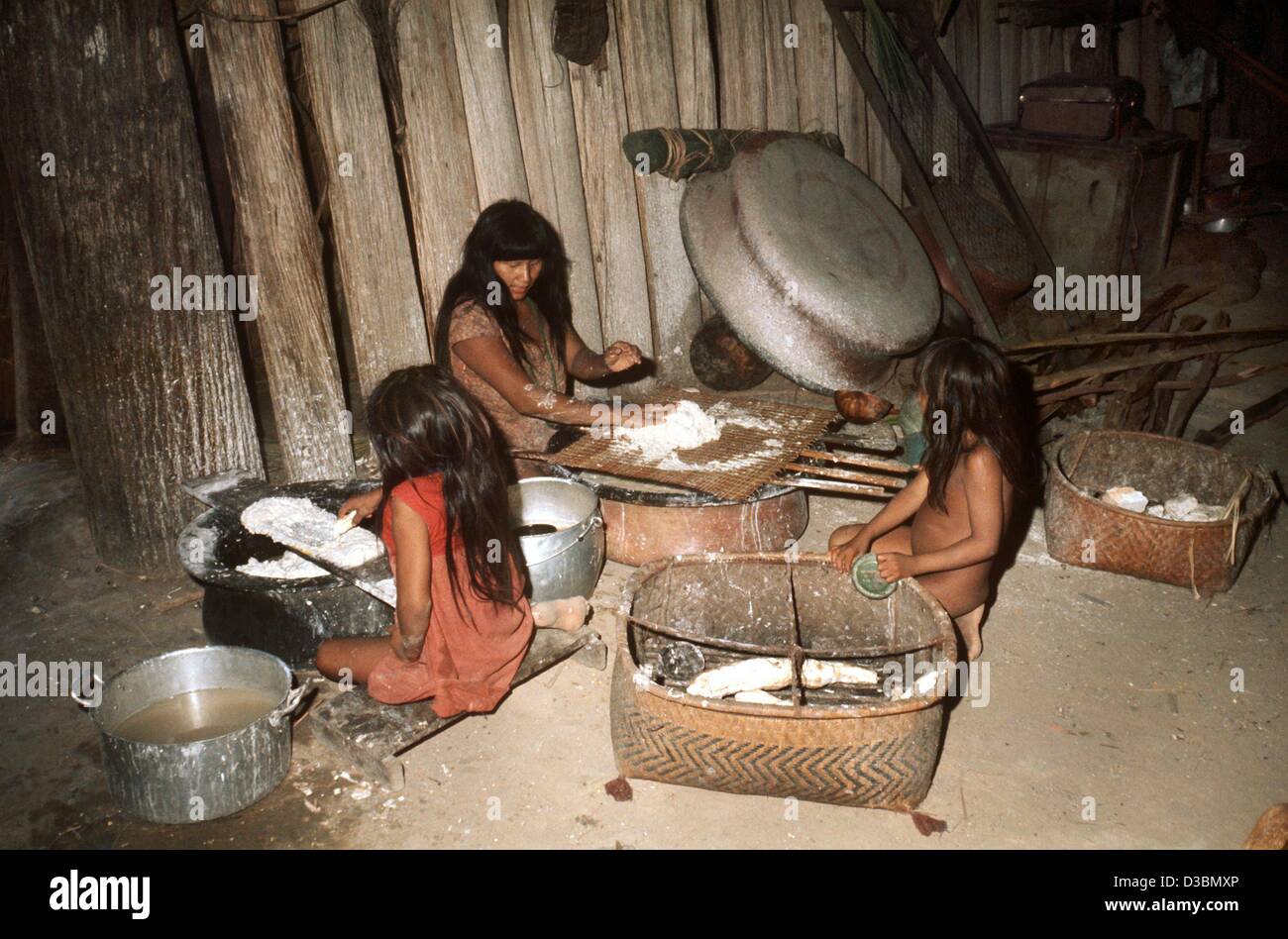 (Afp) - une femme et deux filles de la tribu des Jawalapiti mélanger une pâte de manioc séché, dans une cabane dans le Parc National du Xingu au Brésil, 1976. L'aliment de base des Indiens d'Amazonie est le manioc et la principale source de protéines est le poisson. Bon nombre des compétences agricoles et de chasse de l'original I Banque D'Images