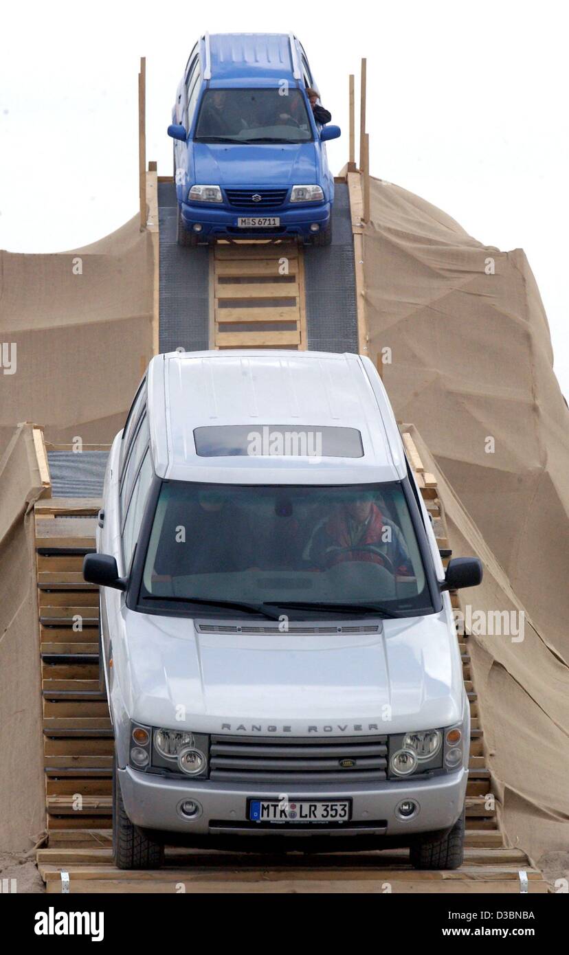 (Afp) - UN Range Rover (avant) et une Suzuki (derrière) y manœuvrer sur un parcours qui a été préparé pour un essai de véhicules tout-terrain à l'IFA (International) location Auto Messe parc des expositions de Leipzig, Allemagne, 5 avril 2003. Les visiteurs de la foire peuvent rejoindre un trajet sur le siège passager. Douze entreprises Banque D'Images