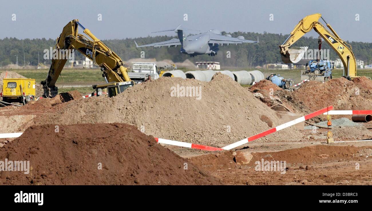 (Afp) - Deux excavatrices sont au travail pendant qu'en arrière-plan un C-17 Globemaster de l'US Air Force prend son envol à partir de l'ancienne piste à la base aérienne US à Ramstein, en Allemagne, le 17 septembre 2003. Construction d'une nouvelle piste a commencé sur la base aérienne. Les coûts sont calculés à environ 60 millions d'euros. Banque D'Images