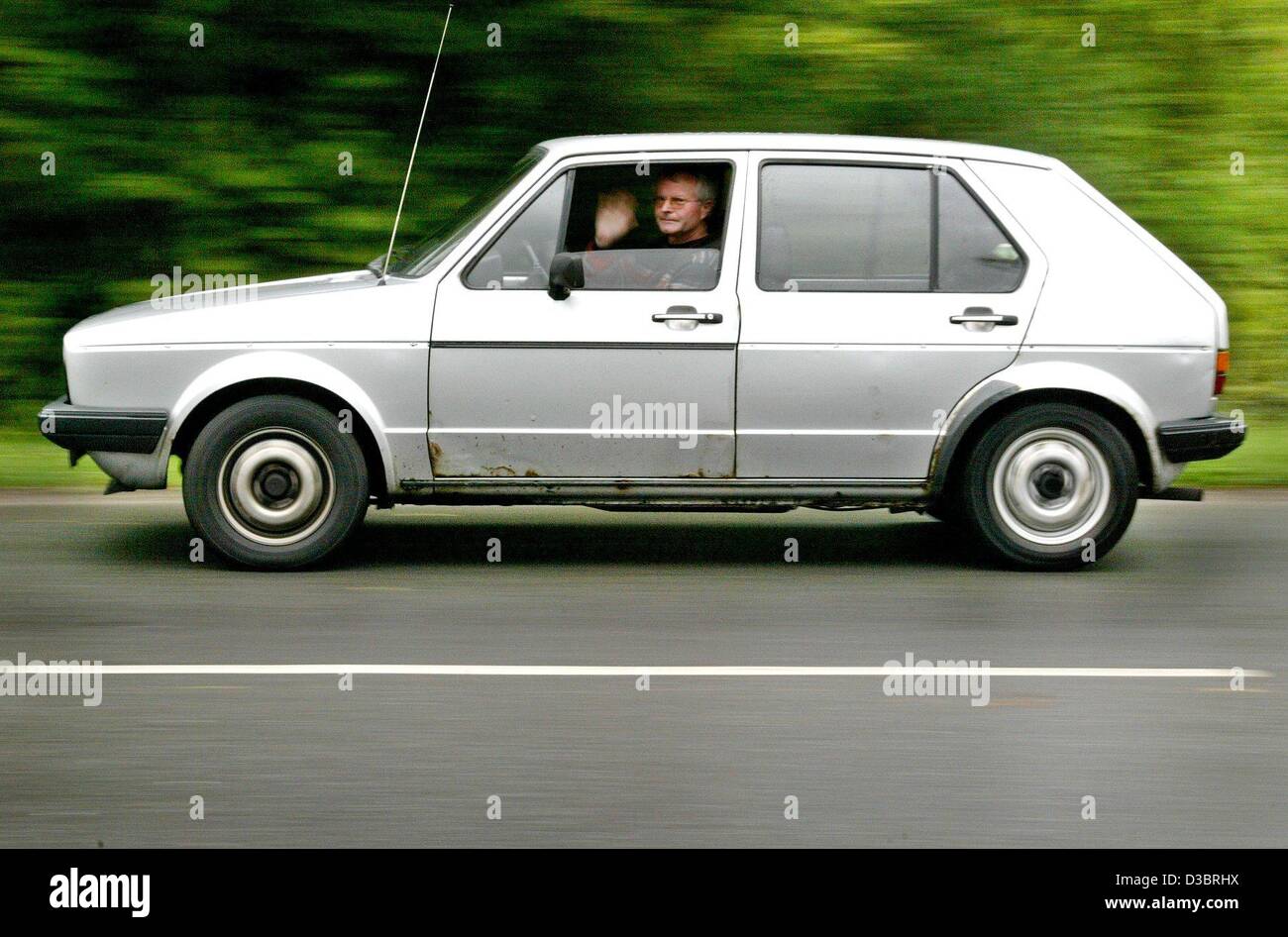 (Afp) - les lecteurs de Hans-Dieter Gehlen sa VW Golf I comme il regarde par la fenêtre et agite sa main à Duisburg, Allemagne, 29 septembre 2003. Gehlen conduit sa Golf les derniers kilomètres en route vers le musée VW de Wolfsburg afin d'atteindre les 1 millions de kilomètres. Le moteur de l'ol 20 ans Banque D'Images