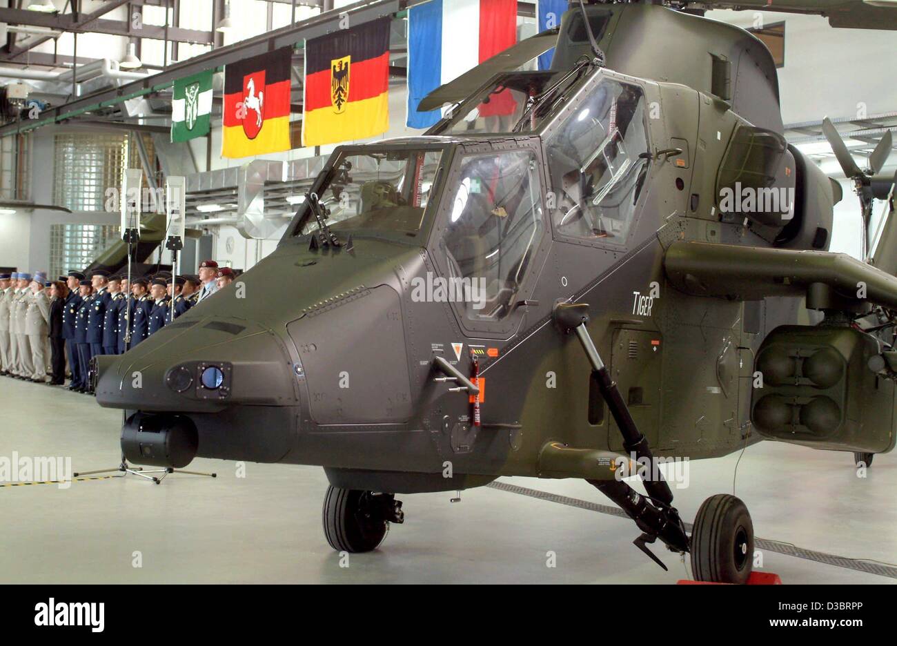 (Afp) - Le nouveau type de l'hélicoptère de combat Tigre (R) se trouve dans le hangar à côté d'un groupe d'unités de formation en français et en allemand (l'arrière), qui se tiennent dans le fichier sous les drapeaux nationaux de l'Allemagne, la France et l'Etat allemand de Basse-Saxe sur la base aérienne à Fassberg, Allemagne, 27 septembre 2003. G Banque D'Images