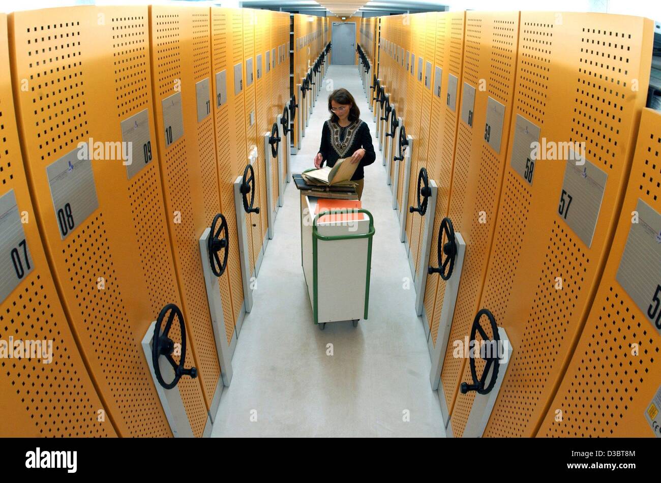 (Afp) - Un employé se place en avant d'un chariot de bibliothèque et d'une recherche dans un fichier dans le référentiel de bas niveau du central public record office de l'état allemand de Thuringe à Weimar, Allemagne, 16 septembre 2003. L'archive a été sujettes à des reconstructions de l'installation qui ajouté Banque D'Images