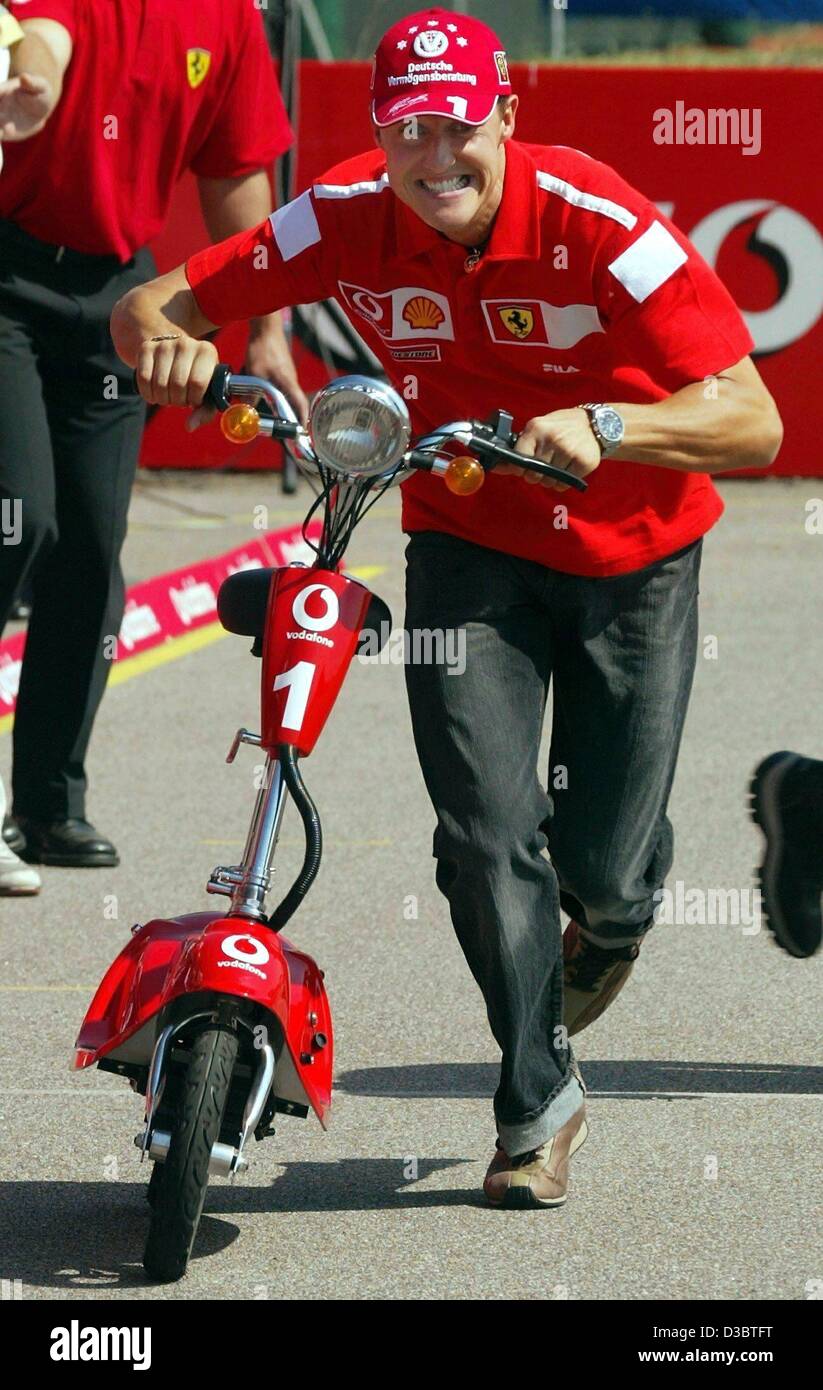 (Afp) - L'Allemand Michael Schumacher, pilote de formule 1 de Ferrari pousse son scooter dans le paddock sur la piste de course à Monza, Italie, le 11 septembre 2003. Le Grand Prix d'Italie aura lieu à Monza le dimanche 14 septembre. Banque D'Images