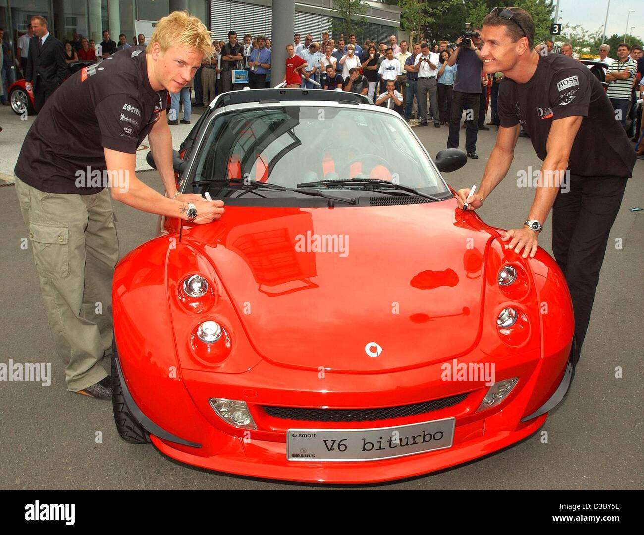 (Afp) - Les deux pilotes de Formule 1 McLaren-Mercedes Kimi Raeikkoenen (L) à partir de la Finlande et de David Coulthard (R) de l'Écosse signer leurs autographes sur le capot d'un nouveau prototype de la Smart Roadster V6 biturbo à l'enceinte de l'usine Smart dans Offenbach, Allemagne, 30 juillet 2003. Banque D'Images