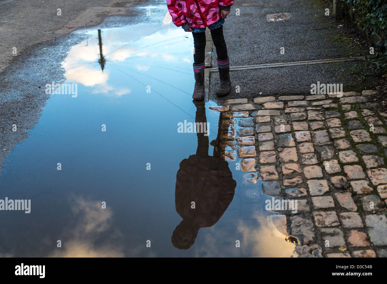 Fille regarde son reflet dans une flaque d'eau Banque D'Images