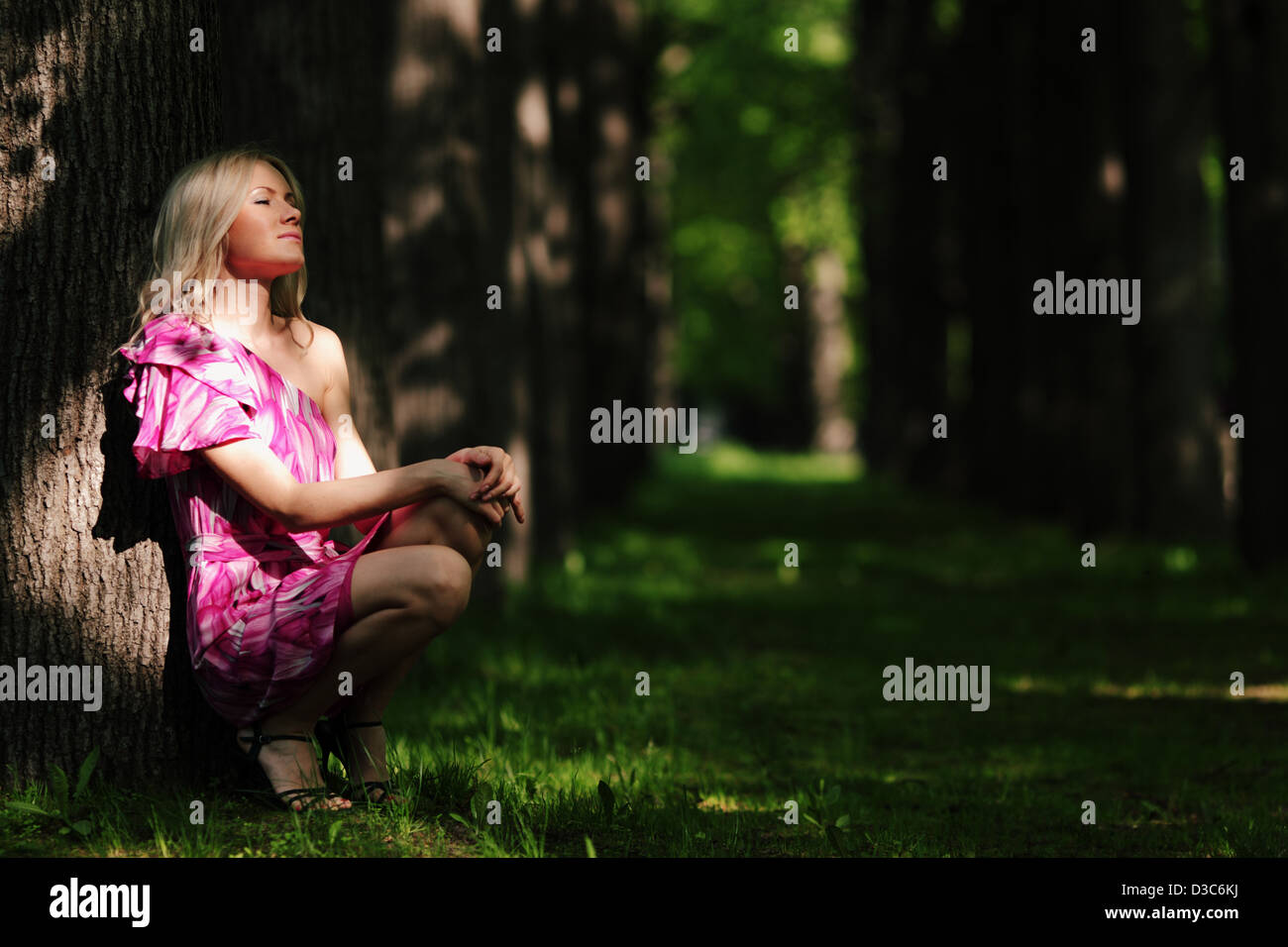 Femme assise sur un parc ombragé alley Banque D'Images