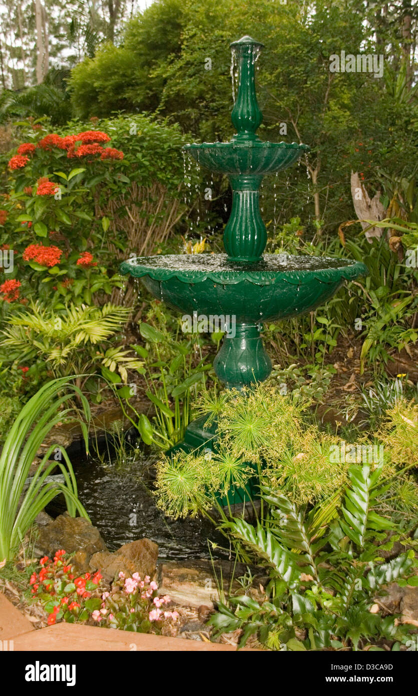 Fontaine à plusieurs niveaux et la piscine - un dispositif de l'eau de design classique entouré de jardin coloré de fleurs et d'arbustes Banque D'Images