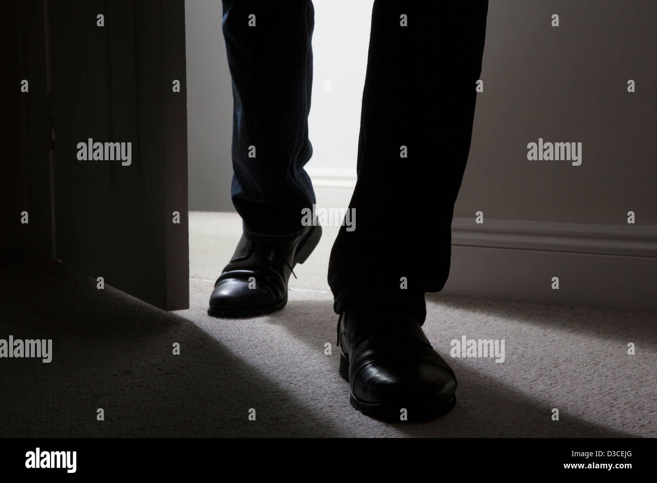 Close up des mâles adultes de jambes et pieds de porter des chaussures noires entre dans une pièce sombre. Silhouette. Banque D'Images