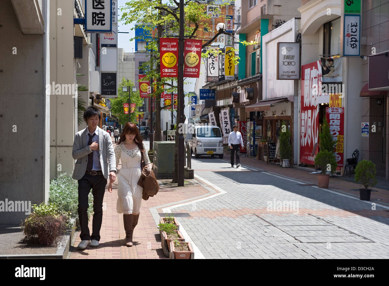 Un jeune couple marchant le long d'une rue commerçante étroite bordée de magasins et de restaurants appelés Nisenro-dori dans la ville de Nagano, au Japon. Banque D'Images