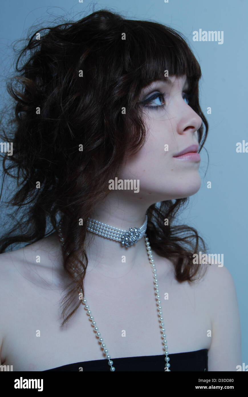 Un gros plan d'une jeune femme blanche modèle avec cheveux bruns portant des bijoux en cristal et perles dans un salon de beauté et studio Banque D'Images