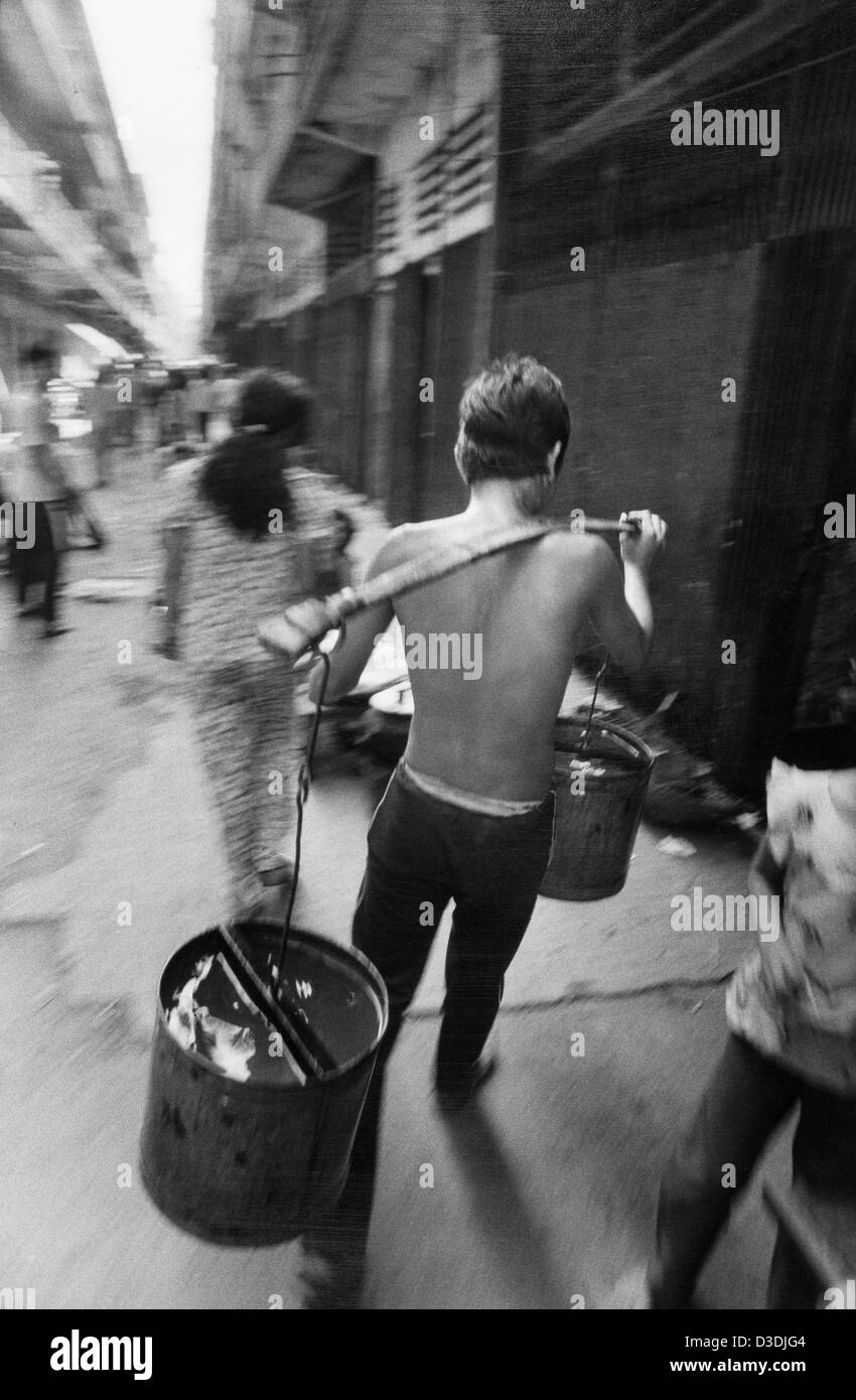 Cambodge : un homme porte l'eau dans son immeuble de la capitale. L'approvisionnement en eau de la région est un tuyau dans la rue. Banque D'Images