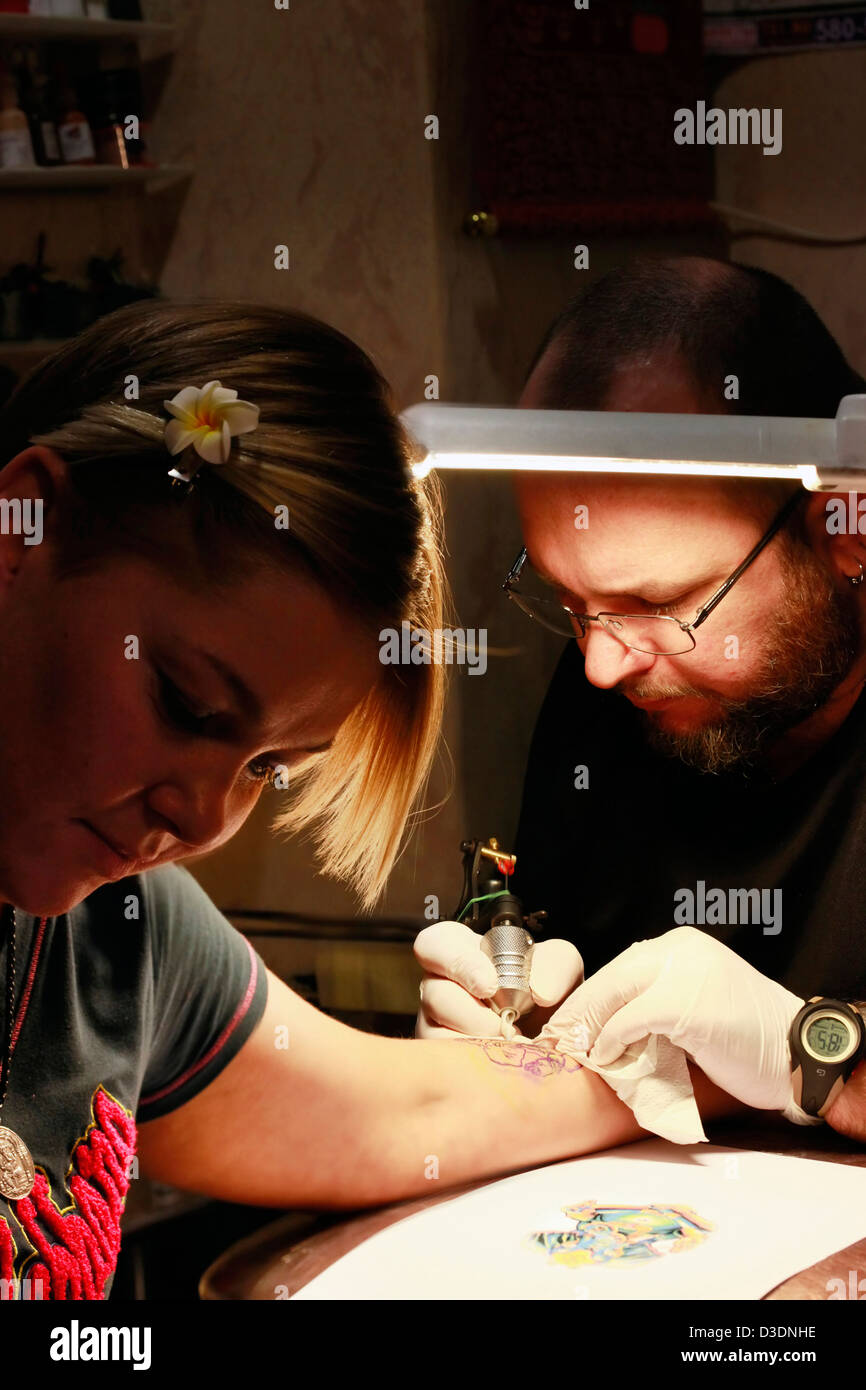 Un tatoueur d'appliquer son art sur la main d'une femme Banque D'Images