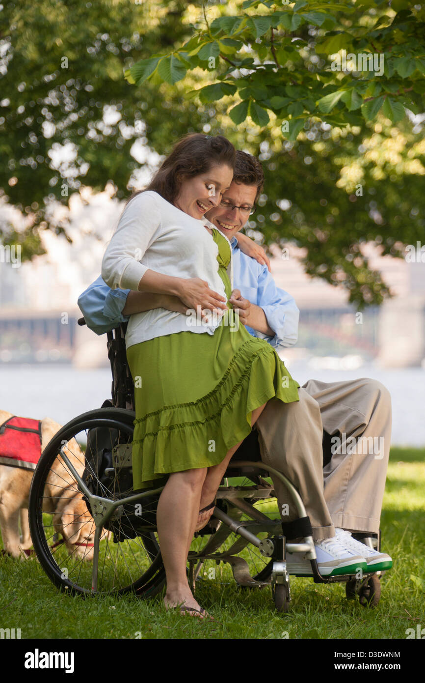 Homme avec une lésion de la moelle épinière dans un sentiment en fauteuil roulant à sa femme le bébé ventre Banque D'Images