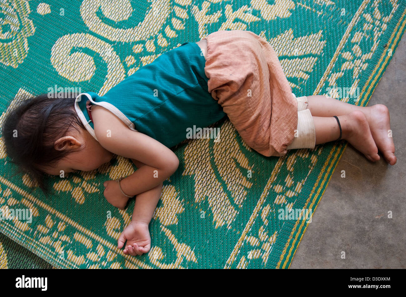 Fang, en Thaïlande, un petit enfant fait une sieste sur le sol Banque D'Images