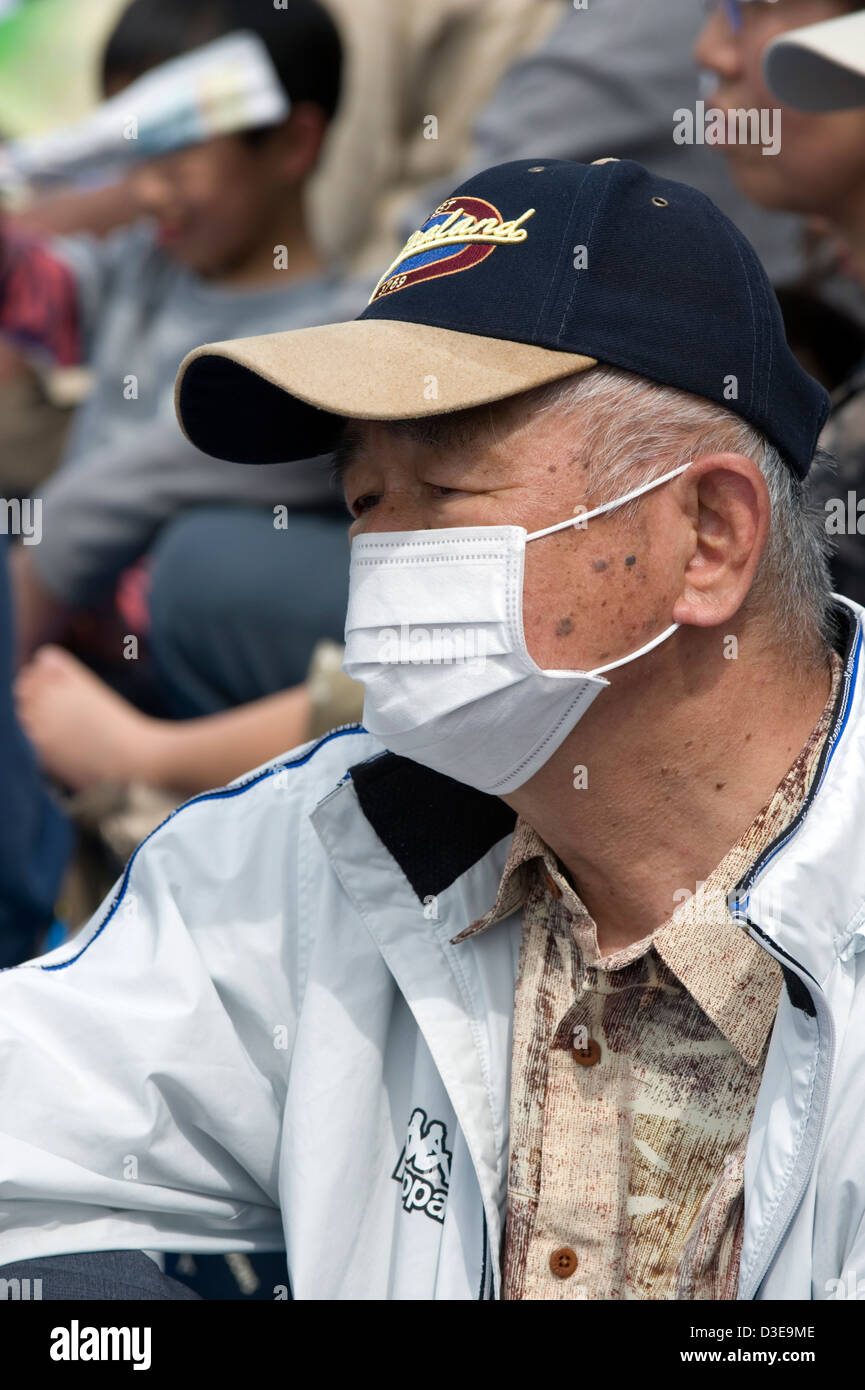 Un vieil homme japonais portant un masque chirurgical de protection pour empêcher la propagation des microbes et de la maladie à des gens autour de lui. Banque D'Images