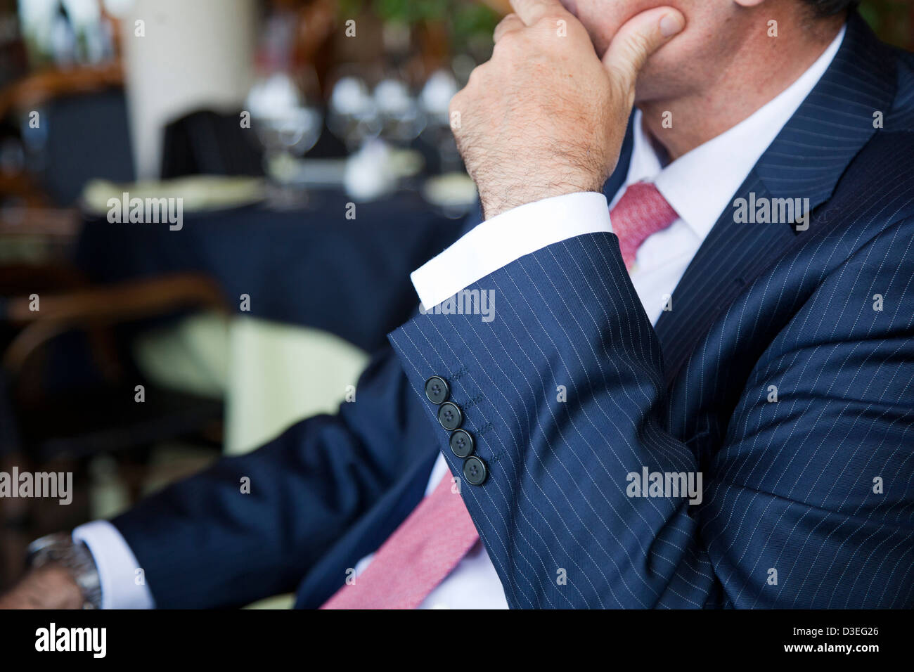 Businessman considérant la situation à une assise à table dans un restaurant au cours d'un déjeuner d'affaires. Banque D'Images