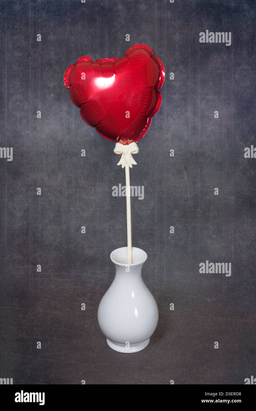Rouge, un ballon en forme de coeur dans un vase blanc Banque D'Images