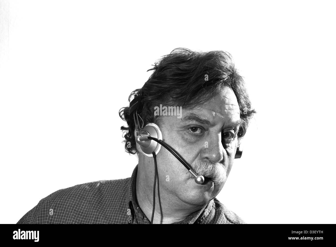 Middle-aged businessman travaille dans les écouteurs avec micro ordinateur derrière, noir et blanc Banque D'Images