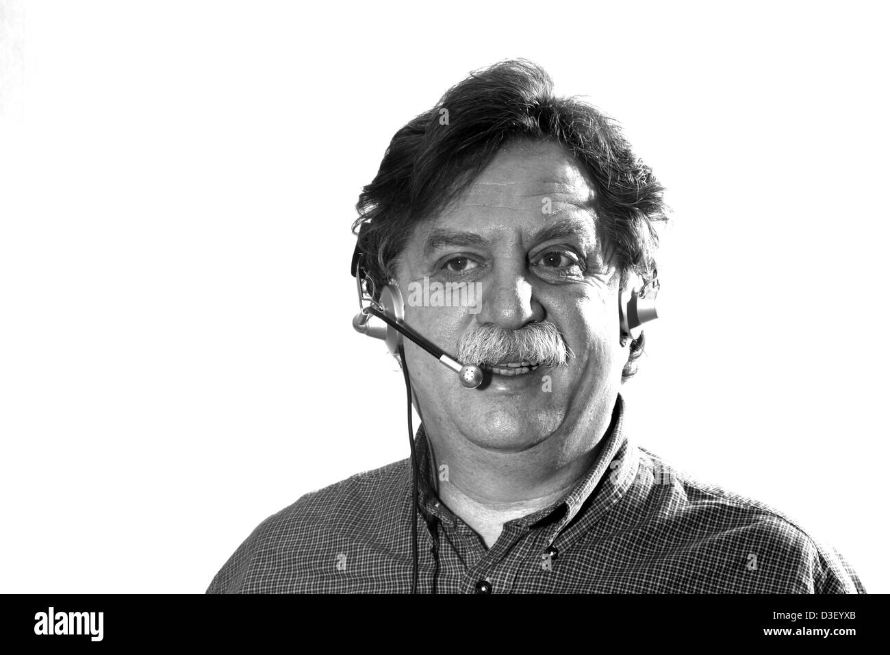 Middle-aged businessman travaille dans les écouteurs avec micro ordinateur derrière, noir et blanc Banque D'Images