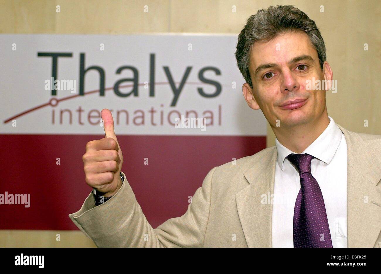 (Afp) - Frank Bernard, président de Thalys International, donne le pouce-up signe devant le logo de l'entreprise sur les résultats conférence de presse à Cologne, Allemagne, 2 juillet 2003. Le train express de Thalys est une entreprise commune des Français, allemand et belge de chemins de fer. Banque D'Images