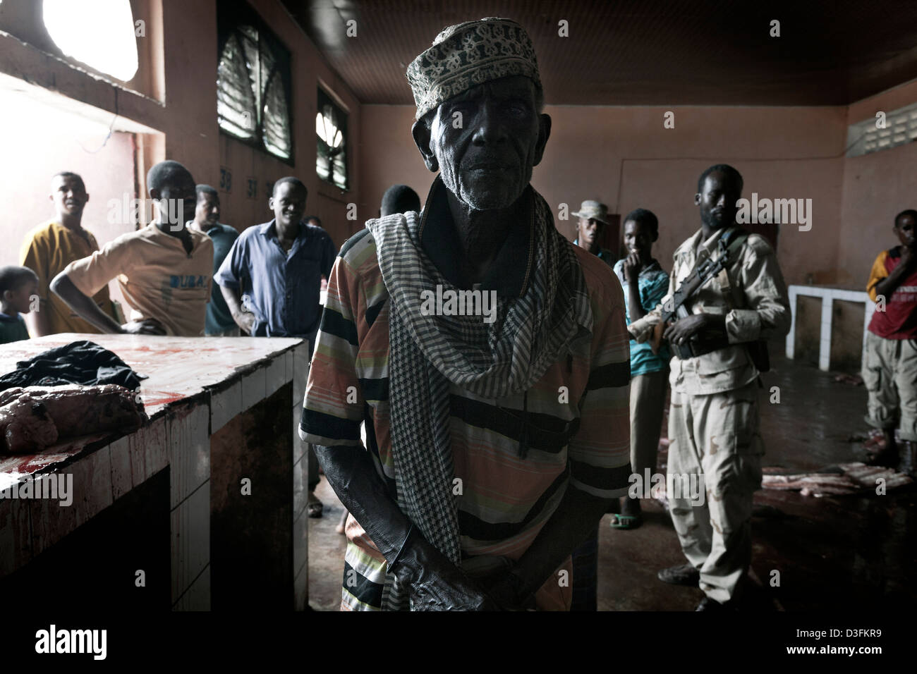Un vieil homme au marché aux poissons de Mogadishu. Dans l'arrière-plan se trouve un soldat du TFG, qui a agi à titre de gardien de sécurité. Banque D'Images