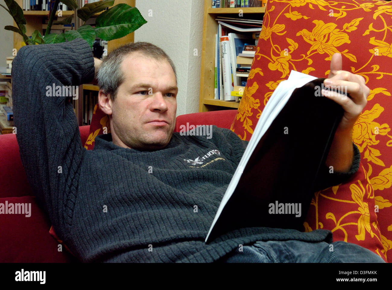 (Afp) - le réalisateur allemand Uwe Boll lit un scénario sur son canapé à Mainz, Allemagne, 3 décembre 2004. Le 39-year-old directeur est intéressée à garder les coûts de ses productions aussi bas que possible. L'homme relativement inconnu n'est pas seulement directeur et producteur de ses films, mais prend également soin des recettes nécessaires et les profits avec son auto-publiés et f Banque D'Images