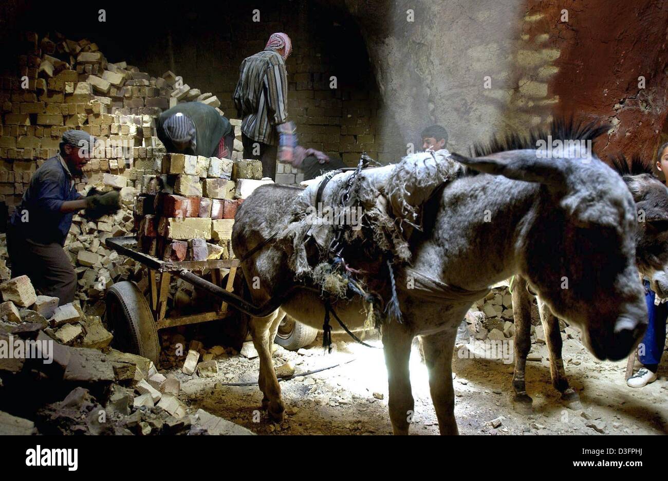 (Afp) - les hommes irakiens briques de charge sur un âne dans un grand four d'une usine de briques dans la périphérie de Najaf, en Irak, le 11 mai 2003. Les briques sont toujours fabriqués de façon traditionnelle dans de nombreux endroits en Iraq. Banque D'Images
