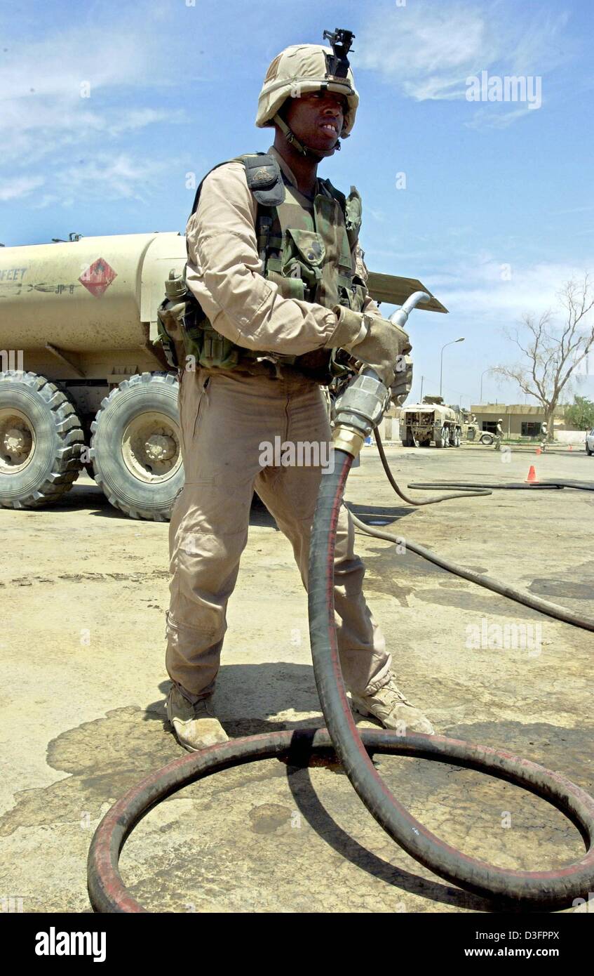 (Afp) - Un soldat américain avec un tuyau se place en avant d'un camion-citerne de l'armée américaine à Bagdad, 8 mai 2003. L'armée américaine a commencé à distribuer de l'essence gratuite, en raison de l'absence de gaz dans l'Iraq. Banque D'Images