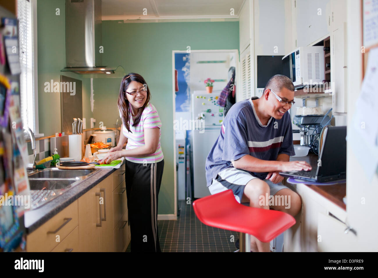 Un couple passer le week-end dans la cuisine où l'épouse de cuisiniers tandis que mari regarde la recette dans l'internet Banque D'Images