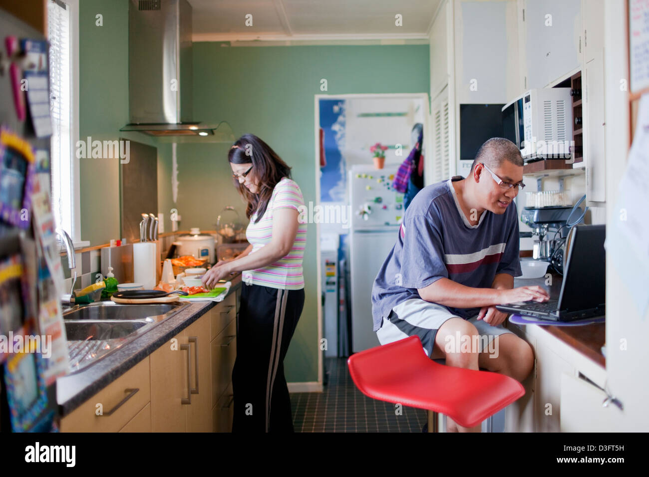 Un couple passer le week-end dans la cuisine où l'épouse de cuisiniers tandis que mari regarde la recette dans l'internet Banque D'Images