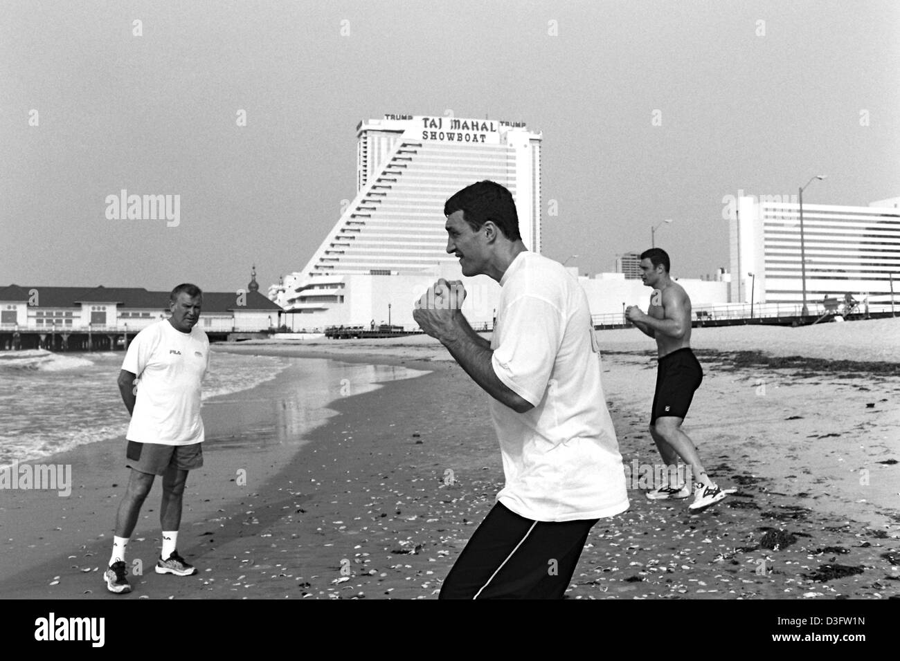 (Afp) - Les boxeurs poids lourd ukrainien Wladimir Klitschko (avant) et son frère Vitali jette quelques coups en l'air sur la plage d'Atlantic City, New Jersey, USA, 28 juin 2002. Sur la gauche de leur entraîneur allemand Fritz Sdunek. Banque D'Images