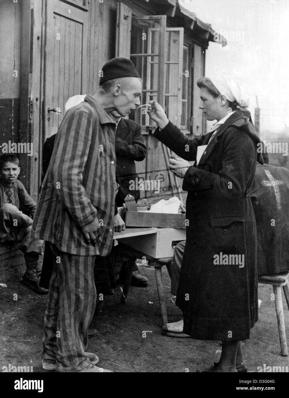 (Afp) - Une infirmière de la Croix-Rouge s'occupe d'un survivant du camp de concentration après la libération d'un camp près de Hanovre, Allemagne, 10 avril 1945. Banque D'Images