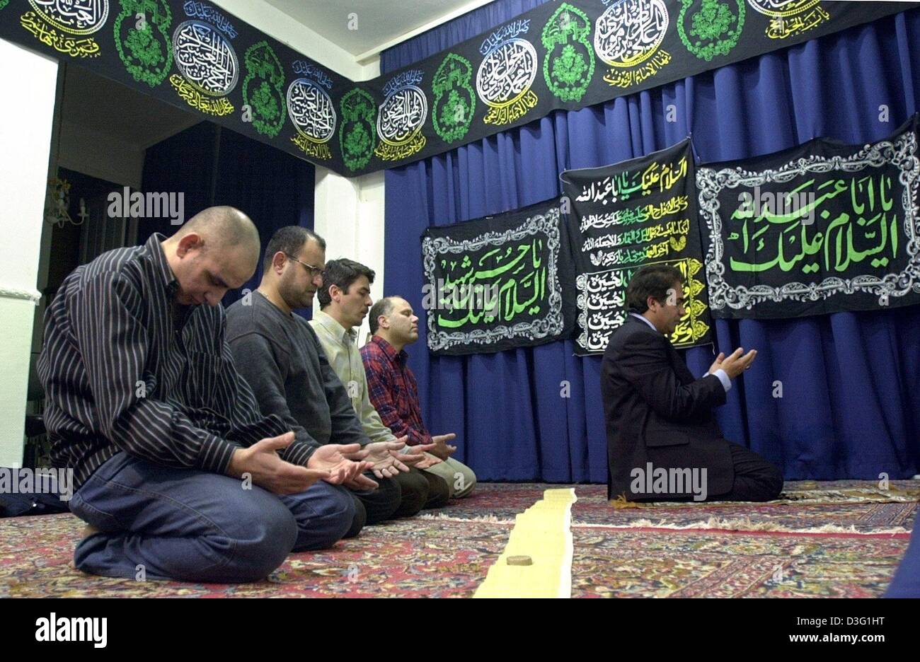 (Afp) - Les irakiens chiites en exil rencontrez pour la prière à une salle de prière dans Hamburg-Billbrook, Allemagne, 20 mars 2003. La salle est drapé d'un bandeau noir sur lequel sont écrits en blanc, vert clair et jaune les noms du prophète et ses douze disciples par worhipped les chiites. Banque D'Images