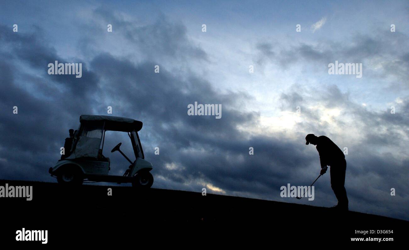 (Afp) - Les nuages d'automne sombre, lourd de la pluie se déplacer lentement sur le ciel passant d'un golf et laissant derrière lui un joueur de golf solitaire qui est sur le point de frapper avec son club en Prenden, Allemagne, 17 novembre 2003. La météo d'automne continue d'être instable. Banque D'Images