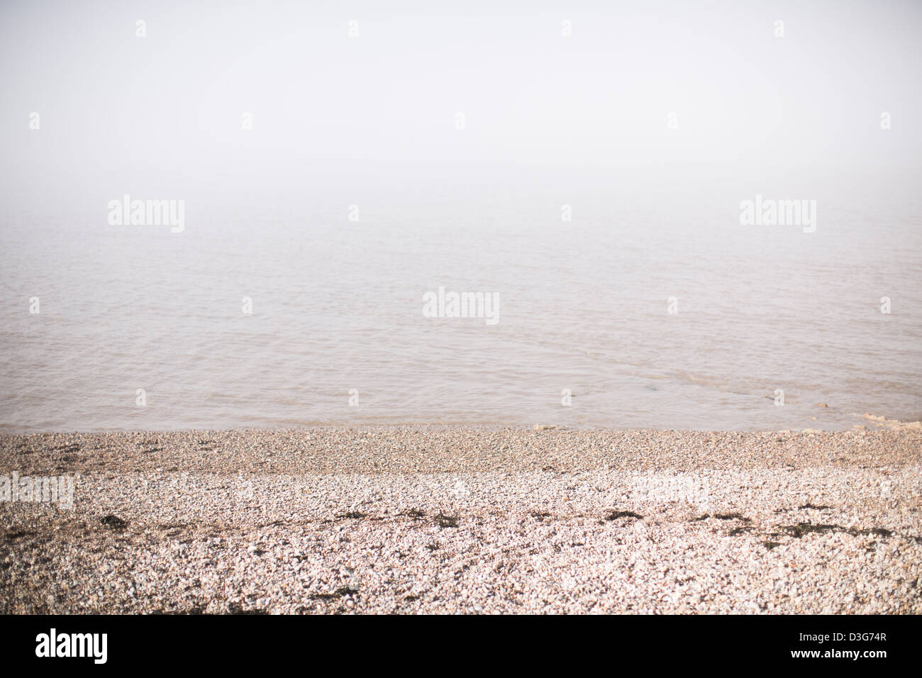 Plage de galets avec pierre clapotis des vagues et la mer obscurcie par le brouillard de l'océan ou sur la mer de brouillard, une forme de nuage bas portant à Clevedon, UK. Banque D'Images