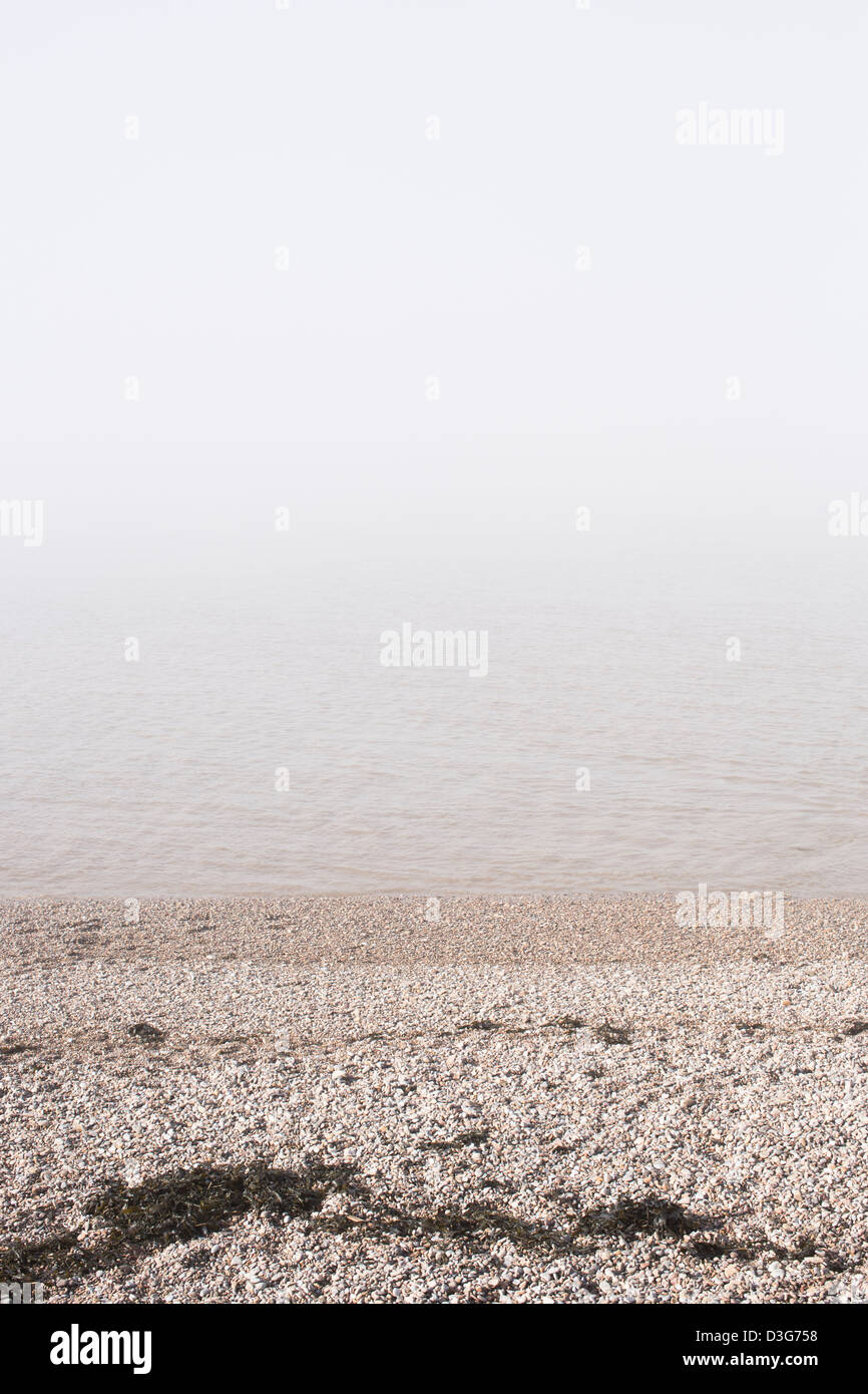 Plage de galets avec pierre clapotis des vagues et la mer obscurcie par le brouillard de l'océan ou sur la mer de brouillard, une forme de nuage bas portant à Clevedon, UK. Banque D'Images