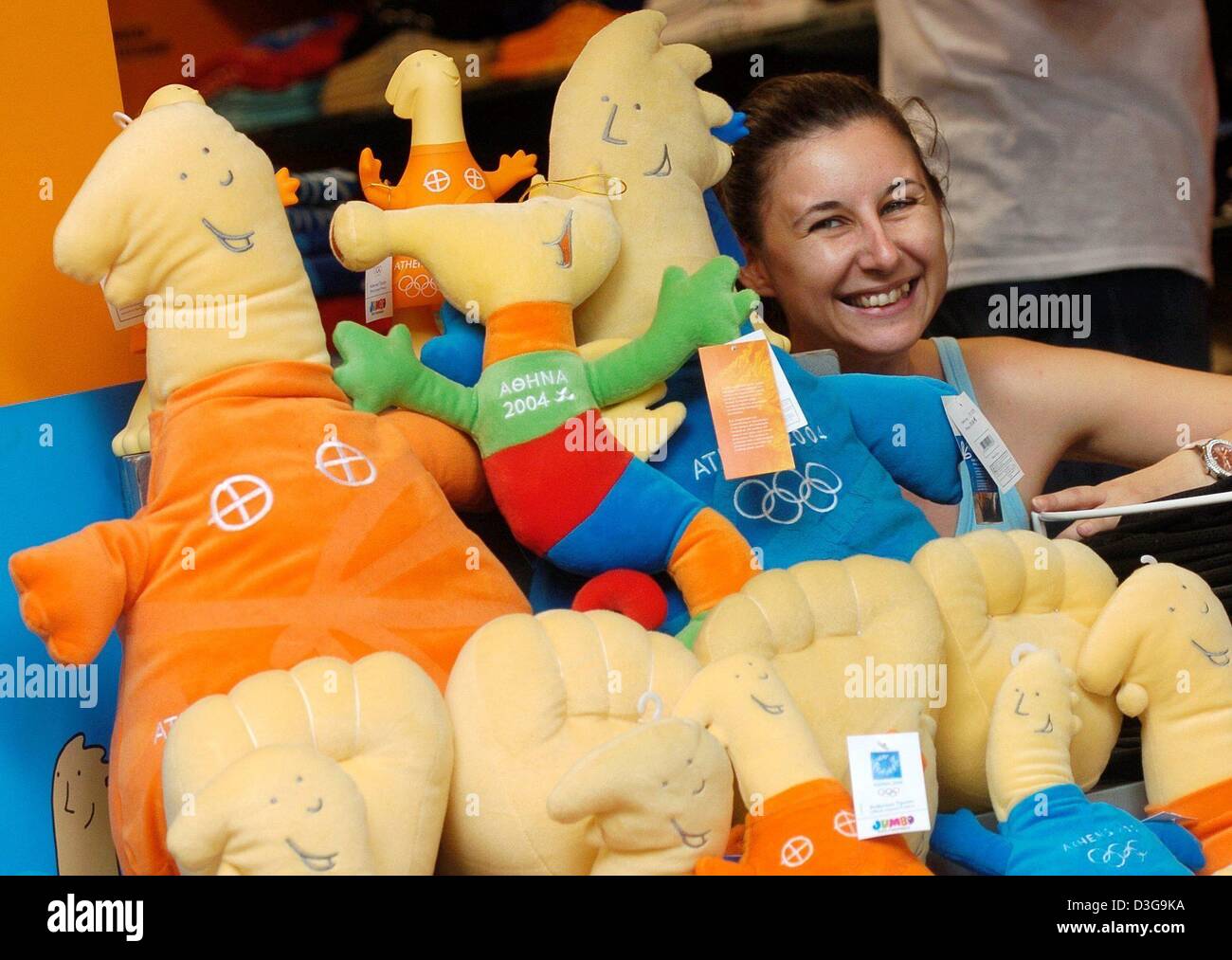 (Afp) - Une fille pose derrière une pile de mascottes olympiques officiels dans une boutique d'Athènes, vendredi 6 août 2004. Les mascottes sont nommés d'après deux dieux de l'Olympe : Phivos, le nom de l'Olympien Dieu de la lumière et de la musique (bleu mascot), connu sous le nom de Apollo ; et Athena (orange mascot), la déesse de la sagesse et saint patron de la ville d'Athènes. Les jeux commencent le 13 août avec la cérémonie d'ouverture Banque D'Images