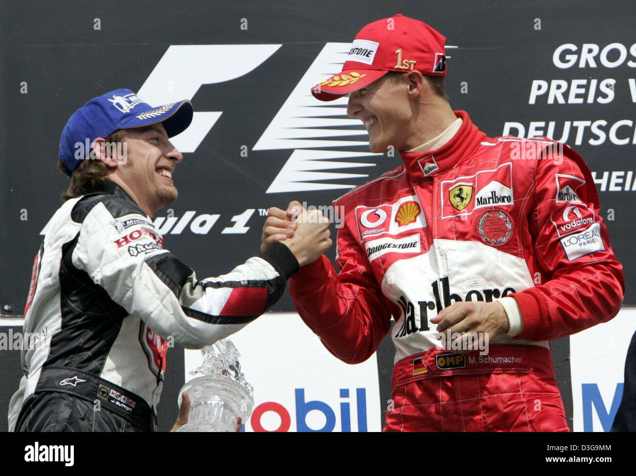 (Afp) - L'Allemand pilote de Formule 1 Michael Schumacher (Ferrari) de l'équipe R, serre la main du pilote britannique Jenson Button (BAR Honda) de l'équipe. Button termine deuxième à Schumacher qui a remporté le Grand Prix d'Allemagne à Hockenheim, Allemagne, 25 juillet 2004. Le champ de formule 1 a remporté un nombre record de 11 de 12 courses cette saison de course. Banque D'Images