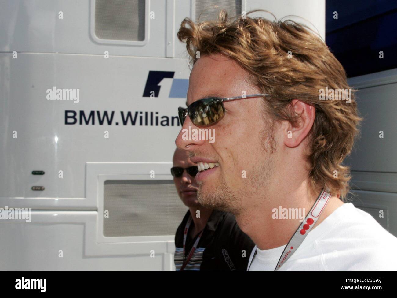 (Dpa) - pilote de Formule 1 britannique Jenson Button (BAR-Honda) de l'équipe passe devant le camping-car de l'équipe BMW-Williams dans le paddock de course sur le Hungaroring, près de Budapest, Hongrie, 12 août 2004. Bouton qui avait l'intention de changer les équipes et prévu de conduire pour BMW-Williams en 2005 demeurera à BAR-Honda pour une autre saison après la reconnaissance des contrats de Formule Un a décidé e Banque D'Images