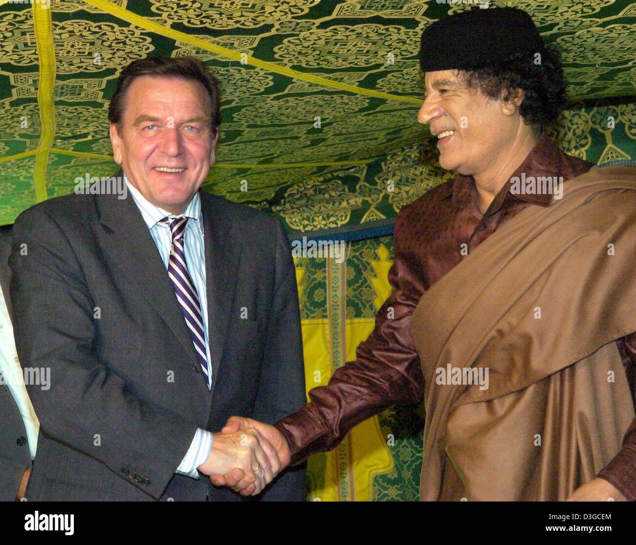 (Afp) - Le Chancelier allemand Gerhard Schroeder (L) est accueilli par le dirigeant libyen Mouammar Kadhafi (R) comme il arrive pour des conférences dans une tente traditionnelle à Tripoli, Libye, jeudi 14 octobre 2004. Schroeder est arrivé ici jeudi soir pour le lancement de son premier de deux jours visite en Libye, la première par un leader allemand de 25 ans. Au niveau politique, les autorités de Berlin a déclaré que la visite Banque D'Images