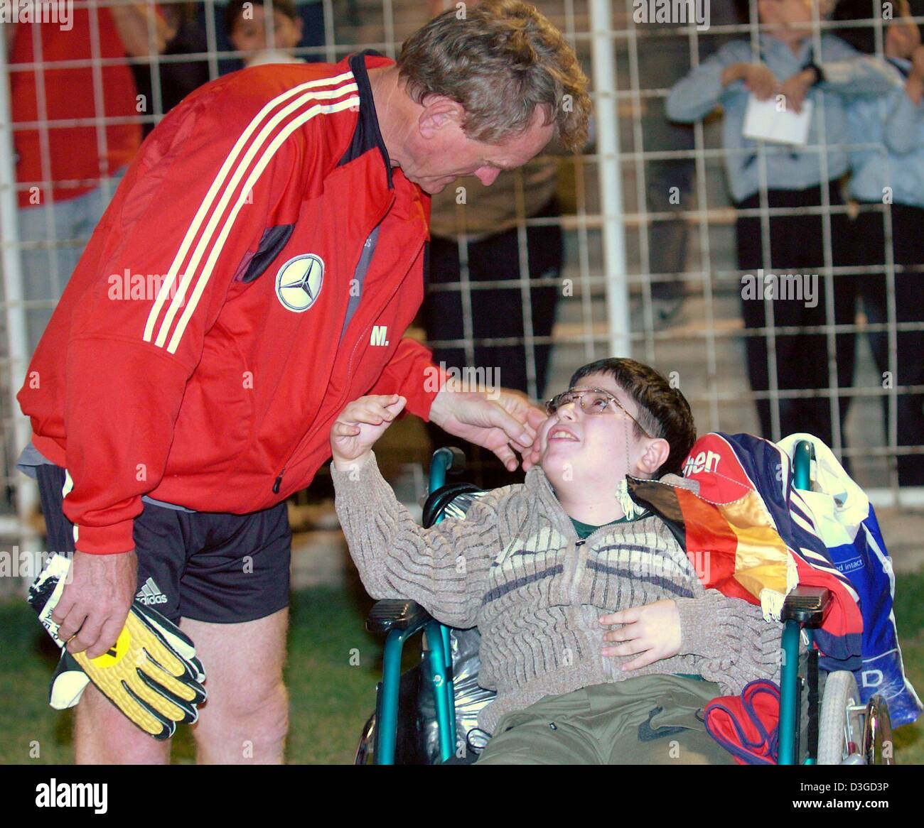 (Afp) - L'entraîneur gardien allemand Sepp Maier accueille un enfant iranien qui est assis dans un fauteuil roulant, à un terrain de football à Téhéran, Iran, 7 octobre 2004. L'équipe de football allemande rencontrera l'équipe nationale dans un match amical le Samedi, 9 octobre 2004. Banque D'Images