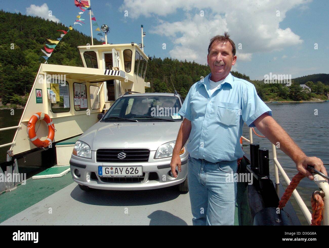 (Afp) - maître Roger Hoell Ferry traverse la rivière Saale au réservoir Hohenwarte lac près de Lüdenscheid, Allemagne de l'Est, 28 juillet 2004. Le ferry qui peut transporter jusqu'à 3 voitures et 20 personnes liens un site de camping au village de Altenroth. Banque D'Images