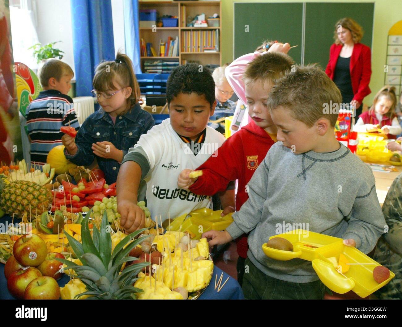 (Afp) - sur leur toute première journée d'école les élèves de la première année de l'école élémentaire la Nordstrasse remplir leur lunch avec fruits frais à Brême, Allemagne, 23 août 2004. Dans le cadre d'un programme sous la devise "l'école de départ avec des vitamines' 5 000 élèves des écoles publiques ont reçu un carton jaune à lunch avec des ingrédients santé, des documents d'information sur une alimentation équilibrée et un wee Banque D'Images