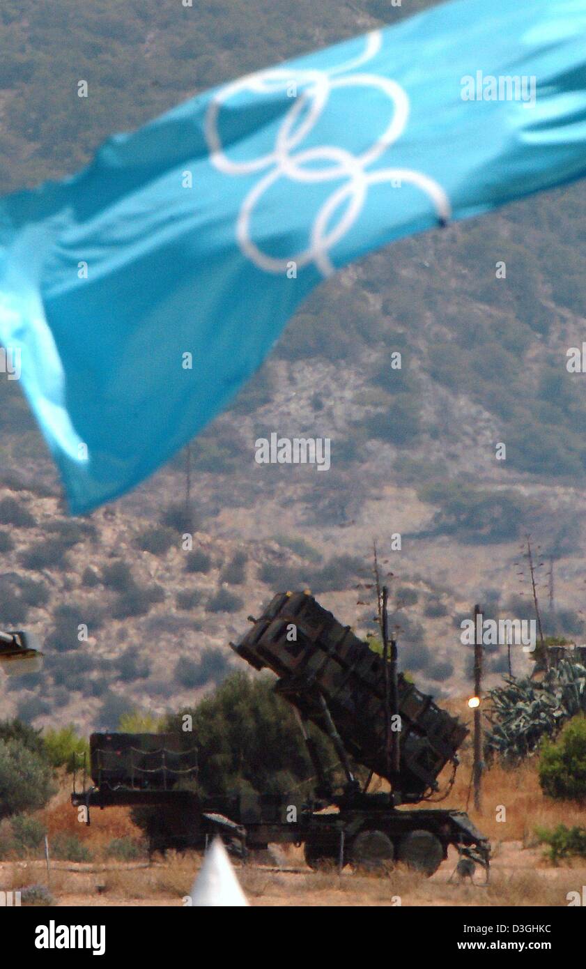 (Afp) - Les drapeaux olympique vagues en face d'un système de missile Patriot stands batterie en stand-by dans le cadre des mesures de sécurité pour les Jeux Olympiques de 2004 près de la complexe olympique Helliniko à Athènes, Grèce, le 30 juillet 2004. Banque D'Images