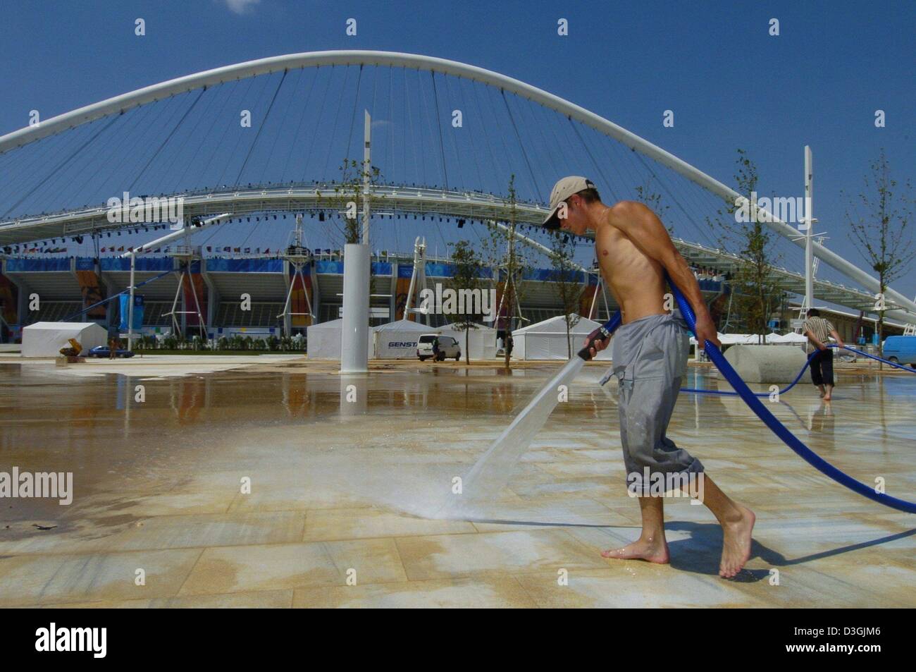 (Afp) - Un employé nettoie le sol en marbre avec un flexible d'eau du parc olympique à Athènes, Grèce, 2 août 2004. Le organziers mettent la touche finale à des sites olympiques. Les Jeux Olympiques d'été 2004 débutera par la cérémonie d'ouverture au Stade olympique à Athènes le 13 août 2004. Banque D'Images