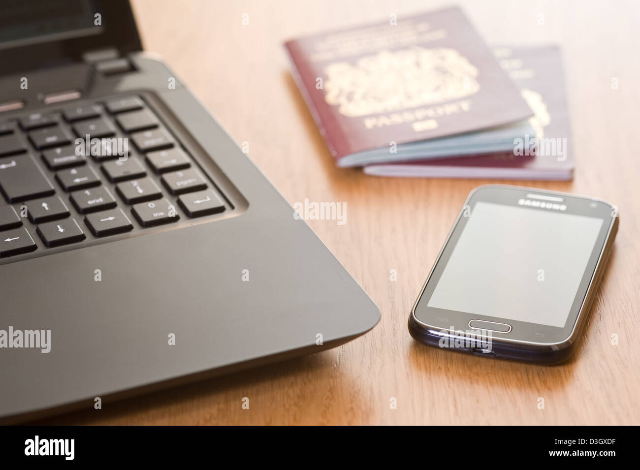 Ordinateur portable, téléphone mobile et deux passeports, sur un bureau. Banque D'Images