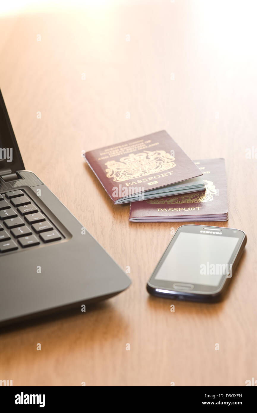 Ordinateur portable, téléphone mobile et deux passeports, sur un bureau. Banque D'Images
