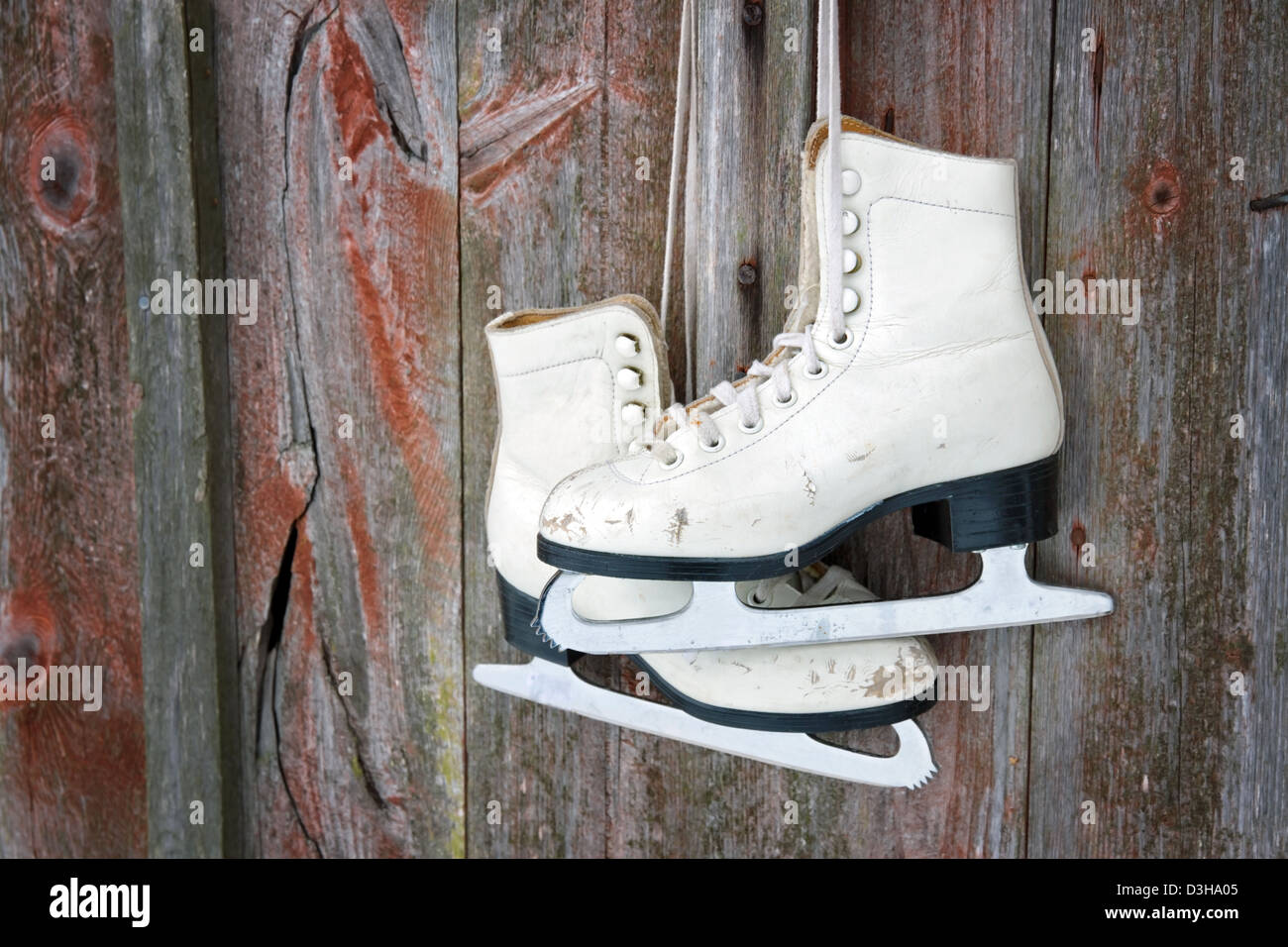 Ancienne figure des patins à glace accrochée à un mur rustique en bois rouge Banque D'Images